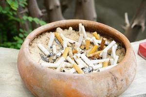 un montón de colillas de cigarrillos en una caja de arena. ambiente contaminado y peligros para los niños foto