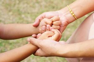 Mother's hand holding a little girl's hand on bokeh background. Love and family concept. photo