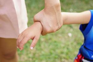 la mano de la madre sosteniendo la mano de una niña en el fondo del bokeh. concepto de amor y familia. foto