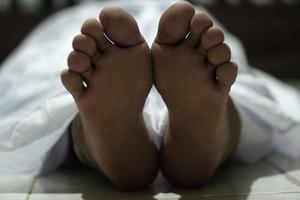 dead body laying on a floor.Focus at the foot photo