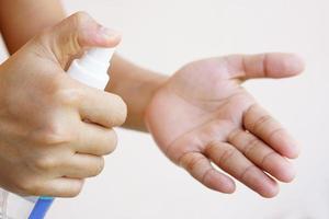 Women's hands using alcohol spray or antibacterial spray to prevent the spread of germs, bacteria and viruses. photo