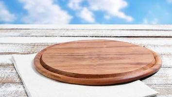 empty pizza board on empty wooden table with tablecloth,napkin - top view photo