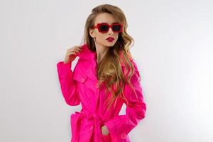 Close up fashion girl in pink clothes and red sunglasses isolated on white background with copy space. Colorful wardrobe and glamour beauty concept. Woman fashion and shopping hobby photo