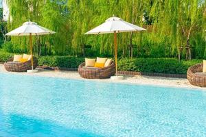 outdoor patio chair with pillow and umbrella around swimming pool photo