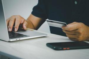 manos masculinas en el teclado de la computadora haciendo transacciones financieras y con tarjeta de crédito o compras en línea en Internet. foto