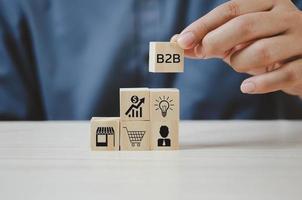 Hand put wooden cubes with  B2B Business to Business icons and symbols on table and copy space.Business concepts. photo