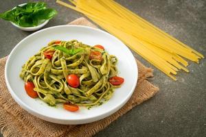 espaguetis fettuccine con salsa pesto y tomates foto