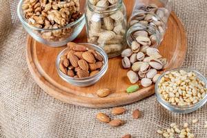 Almonds, pistachios, pine nuts and walnuts on a wooden kitchen board with burlap