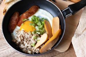 desayuno inglés con huevo frito con cerdo picado y salchicha tailandesa llamada kai kara servida en una cacerola pequeña foto
