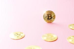 cierre la moneda bitcoin dorada sobre fondo rosa. símbolo de criptomoneda. la moneda de oro bitcoin brillante se destaca entre otras monedas con espacio de copia. foto