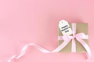 Mother's day background. Top view of gift box with pink bows - long ribbon , beautiful flowers and card on pastel pink background with copy space photo