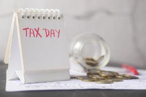 tax day concept with calendar, coins and paper on table photo