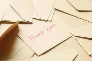 thank you message and envelope on wooden table photo