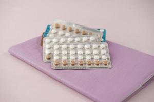 birth control pills on wooden background, close up photo