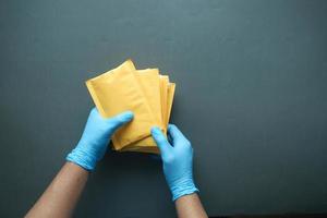 mano en guantes de látex con sobre de burbujas de papel blanco para envío postal. foto