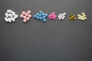 top view of any colorful pills and capsules on black background photo