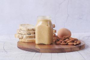 mantequilla de almendras en un recipiente, pan y huevos en la mesa foto