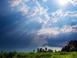 haz de luz solar detrás de nubes oscuras en el campo foto