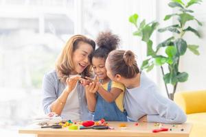 Adorable little child mould from plasticine with mother and grandmother, Grandmother and grandchildren playing cheerfully in living room photo