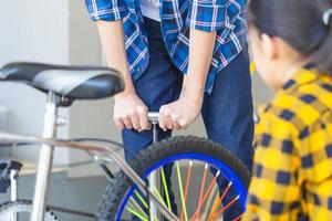 Brother and sister fixing bicycle together, Boy and girl repairing bicycle photo