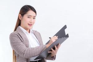 mujeres de negocios asiáticas escribiendo documentos en el portapapeles en la mano mientras trabajan en casa. foto