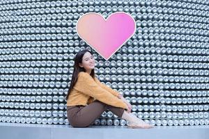 Asian pretty woman in long hair wears a yellow sweater and brightly smiles in Valentine s theme. photo