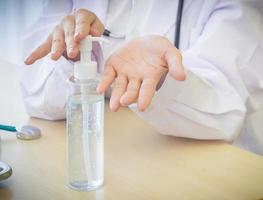 A woman doctor in white lab coat sit and pump the alcohol gel to clean her hands photo