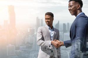 Welcome to our team. young modern men in smart casual wear shaking hands. Two smiling businessmen shaking hands together. Two confident businessmen shaking hands and looking for the future. photo