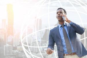 empresarios que usan teléfonos inteligentes en la ciudad con el logo mundial. retrato de un apuesto hombre de negocios. hombre de negocios moderno. joven seguro de sí mismo de pie al aire libre con el paisaje urbano en el fondo foto