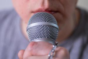 A man speaks into a microphone in close-up. photo