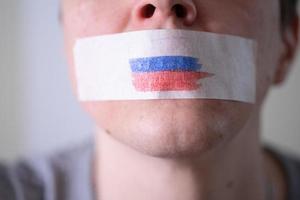 A duct-taped mouth with a Russian flag, trying to say. photo