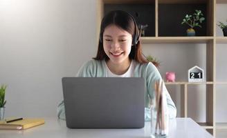 Smart asian young girl student feel satisfied during internet online video conference and searching information via laptop computer at home photo