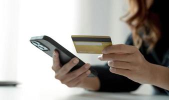 mujer asiática revisando los detalles del pedido en línea en el control cercano del teléfono inteligente de la información de la tarjeta de crédito ingresada. foto