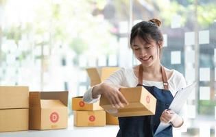 Starting small businesses SME owners female entrepreneurs Use a laptop or notebook to receive and review orders online to prepare to pack boxes, sell to customers, SME online business ideas. photo