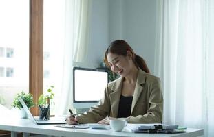 Young Asian businesswoman taking notes using a tablet at the modern office. photo