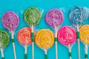 Candy in the form of colorful lollipops on a blue background.