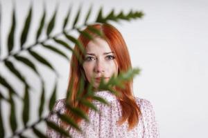 mujer adulta media escondiéndose detrás de hojas de palma de la planta de la casa foto