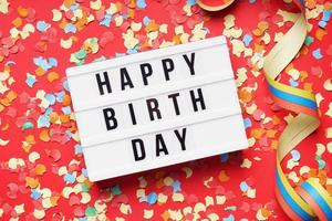 happy birthday flat lay design with lightbox sign and confetti photo