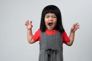 Portrait of Asian angry and sad little girl on white isolated background, The emotion of a child when tantrum and mad, expression grumpy emotion. Kid emotional control concept photo