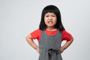 retrato de una niña asiática enojada y triste sobre un fondo blanco aislado, la emoción de un niño cuando berrinche y enojado, expresión de emoción gruñona. concepto de control emocional infantil foto