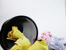 A small black basket made of round iron fell down. It is used to put the trash, documents that are not working and are overflowing to the outside. In the white background there is a copy space. photo