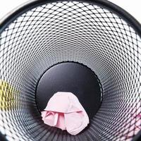 Inside a small black basket made of round iron fell down. It is used to put the trash, documents that are not working and are overflowing to the outside. photo