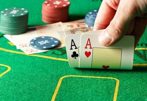 Closeup of poker player with two aces on a poker table. Horizontal image.