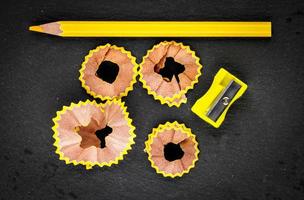 Yellow shavings pencil, yellow sharpener and yellow pencil on black background. Horizontal image. photo