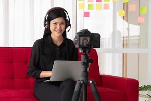 Vlog Asian woman blogger influencer sitting on the sofa in home and recording video blog for teaching and coach her Students or subscriber. Concept of the content creator online for a new lifestyle photo
