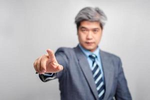 Selective focus of index finger of Asian senior businessman in a suit on white background isolated background. The concept of communication, technology, and connection photo