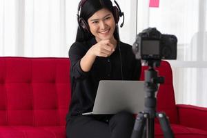 Vlog Asian woman blogger influencer sitting on the sofa in home and recording video blog for teaching and coach her Students or subscriber. Concept of the content creator online for a new lifestyle photo