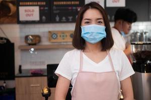 mujeres baristas asiáticas que usan máscaras faciales para prevenir enfermedades contagiosas y atender a los clientes en la cafetería. el concepto de prevención de covid 19 foto