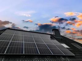 Roof window in velux style with black roof tiles and some solar panels photo