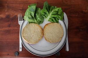 Homemade making of a grilled burger with tomatoes and salad on a plate photo